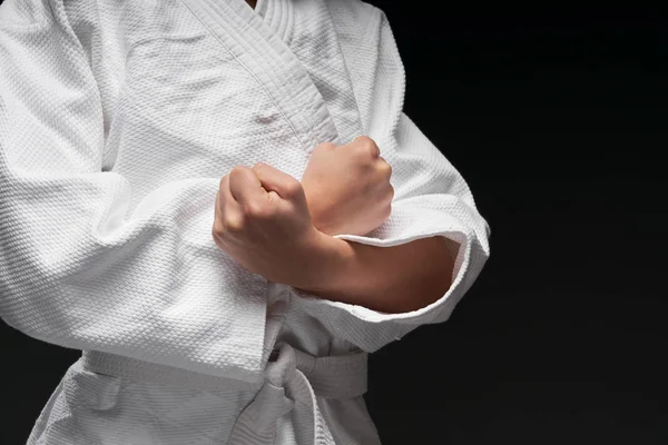 Hands close up of a teenager athlete, dressed in martial arts clothing poses on a dark gray background, a sports concept — Stock Photo, Image