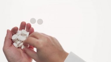 Beyaz arka planda haplar, haplar, vitaminler, ilaçlar, kapsüller olan bir adam eli. Beyaz gömlek, iş tarzı. Sağlık hizmeti konsepti. İlaç sanayisi. Eczane.