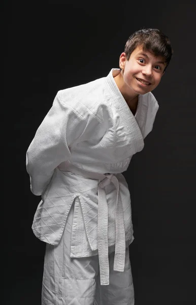 Concepto de deporte - un adolescente vestido con ropa de artes marciales posa sobre un fondo gris oscuro, sesión de estudio — Foto de Stock