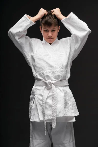 Conceito de esporte adolescente irritado vestido com roupas de artes marciais posa em um fundo cinza escuro, tiro estúdio — Fotografia de Stock