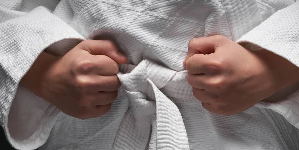 Manos de cerca - adolescente vestido con ropa de artes marciales posando sobre un fondo gris oscuro, un concepto deportivo —  Fotos de Stock