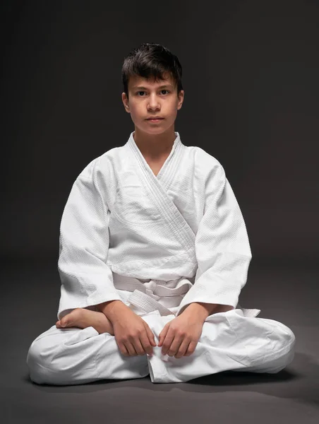 武道の服装をした10代の若者の肖像画は暗い灰色の背景とスポーツの概念に基づいています — ストック写真