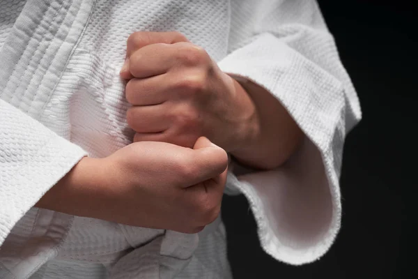 Руки крупным планом - подросток одет в одежду боевых искусств позируя на темно-сером фоне, спортивная концепция — стоковое фото