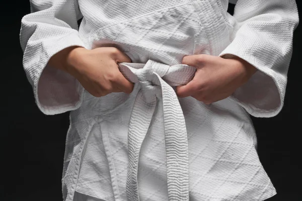 Mãos close-up - adolescente vestido com roupas de artes marciais posando em um fundo cinza escuro, um conceito de esportes — Fotografia de Stock