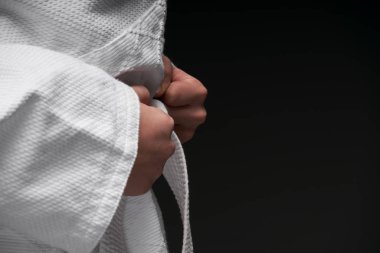 Eller yakın - dövüş sanatları kıyafeti giymiş bir genç koyu gri bir arka planda poz veriyor, bir spor konsepti