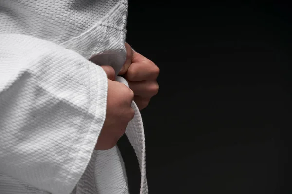 Руки крупным планом - подросток одет в одежду боевых искусств позируя на темно-сером фоне, спортивная концепция — стоковое фото