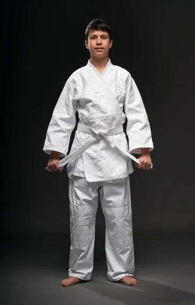 武道の服装をした10代の若者は濃い灰色の背景スポーツの概念に身を包み — ストック写真