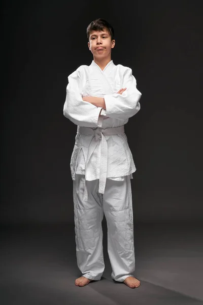 Porträtt av en tonåring klädd i kampsport kläder poser på en mörkgrå bakgrund, en sport koncept — Stockfoto