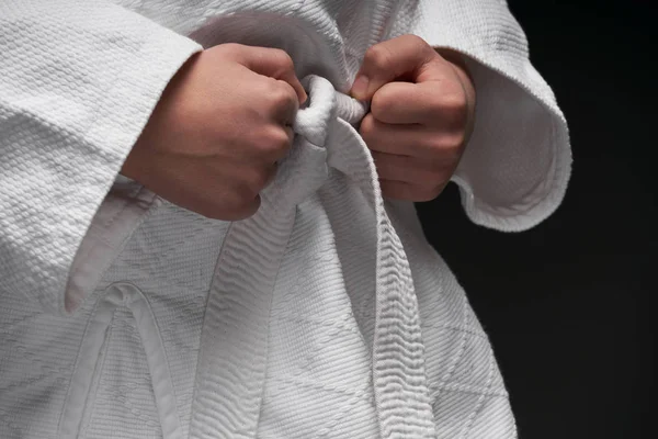 Mãos close-up - adolescente vestido com roupas de artes marciais posando em um fundo cinza escuro, um conceito de esportes — Fotografia de Stock