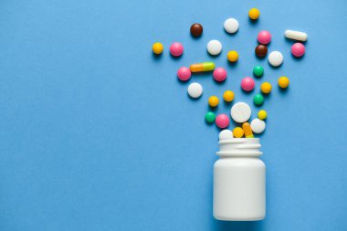 Çeşitli ilaç hapları, haplar, patlayan kapsüller ya da mavi arka plandaki şişeden fışkırma. Metin için boşluk kopyala - ilaç tedavisi kavramı, sağlık hizmetleri