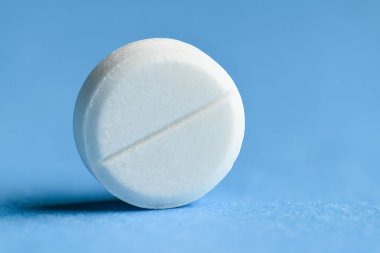 Mavi arka plan makro fotoğraf üzerine beyaz bir hap - ilaç ve ilaç tedavisi konsepti, sağlık hizmetleri