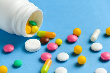 Mavi arka planda çeşitli ilaç hapları, tabletler, kapsüller ve şişeleri kapatın. İlaç tedavisi kavramı, sağlık hizmetleri