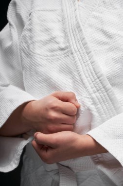 Eller yakın - dövüş sanatları kıyafeti giymiş bir genç koyu gri bir arka planda poz veriyor, bir spor konsepti