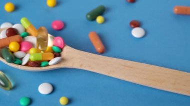 Hap, tablet, vitamin, ilaç, omega 3 balık yağı, jel kapsülleri, ilaç ve sağlık hizmetleri için gıda takviyesi dolu tahta kaşık. Mavi arkaplan.