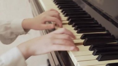 Eski piyano çalan genç bir kızın yakın çekimi.