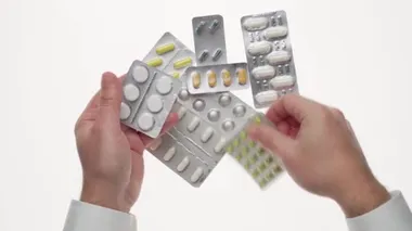 Beyaz arka planda haplar, haplar, vitaminler, ilaçlar, kapsüller olan bir adam eli. Beyaz gömlek, iş tarzı. Sağlık hizmeti konsepti. İlaç sanayisi. Eczane.