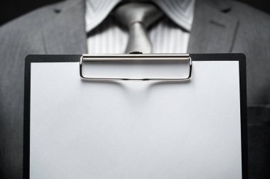 Beyaz boş kağıt sayfa, iş adamı eli, gri takım elbise, koyu duvar arkaplan, metin için boş alan