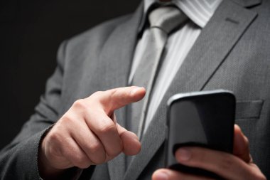 Gri takım elbiseli iş adamı portresi, akıllı telefonla arama, karanlık duvar arka planı