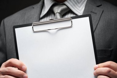 Beyaz boş kağıt sayfa, iş adamı eli, gri takım elbise, koyu duvar arkaplan, metin için boş alan