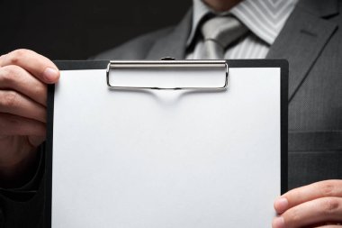 Beyaz boş kağıt sayfa, iş adamı eli, gri takım elbise, koyu duvar arkaplan, metin için boş alan
