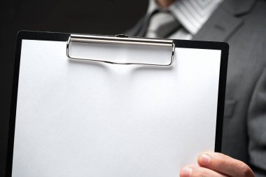 Beyaz boş kağıt sayfa, iş adamı eli, gri takım elbise, koyu duvar arkaplan, metin için boş alan