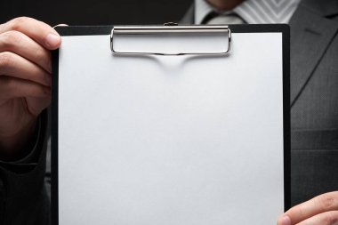 Beyaz boş kağıt sayfa, iş adamı eli, gri takım elbise, koyu duvar arkaplan, metin için boş alan