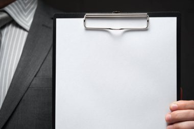 Beyaz boş kağıt sayfa, iş adamı eli, gri takım elbise, koyu duvar arkaplan, metin için boş alan