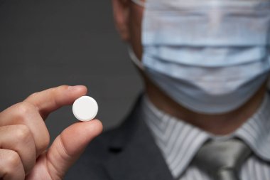 Yüzünde antivirüs şahsi koruması için maske takan bir adam ilaç gösteriyor - sağlık ve tıp konsepti, önleme ipuçları