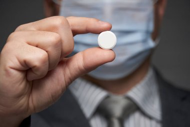 Yüzünde antivirüs şahsi koruması için maske takan bir adam ilaç gösteriyor - sağlık ve tıp konsepti, önleme ipuçları
