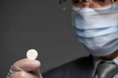 Yüzünde antivirüs şahsi koruması için maske takan bir adam ilaç gösteriyor - sağlık ve tıp konsepti, önleme ipuçları