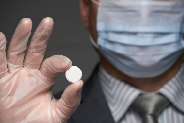 Yüzünde antivirüs şahsi koruması için maske takan bir adam ilaç gösteriyor - sağlık ve tıp konsepti, önleme ipuçları