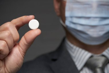 Yüzünde antivirüs şahsi koruması için maske takan bir adam ilaç gösteriyor - sağlık ve tıp konsepti, önleme ipuçları