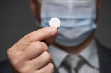 Yüzünde antivirüs şahsi koruması için maske takan bir adam ilaç gösteriyor - sağlık ve tıp konsepti, önleme ipuçları