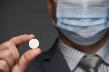 Yüzünde antivirüs şahsi koruması için maske takan bir adam ilaç gösteriyor - sağlık ve tıp konsepti, önleme ipuçları