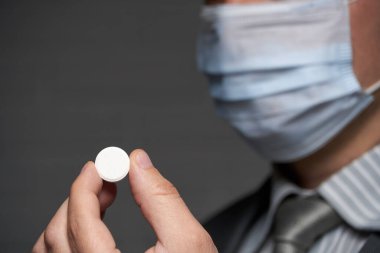Yüzünde antivirüs şahsi koruması için maske takan bir adam ilaç gösteriyor - sağlık ve tıp konsepti, önleme ipuçları