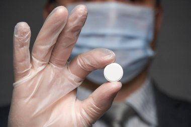 Yüzünde antivirüs şahsi koruması için maske takan bir adam ilaç gösteriyor - sağlık ve tıp konsepti, önleme ipuçları