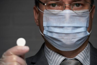 Yüzünde antivirüs şahsi koruması için maske takan bir adam ilaç gösteriyor - sağlık ve tıp konsepti, önleme ipuçları