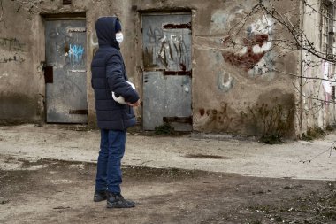 Salgın ve karantina kavramı - yüz maskeli bir çocuk ve şehirde tek başına top.