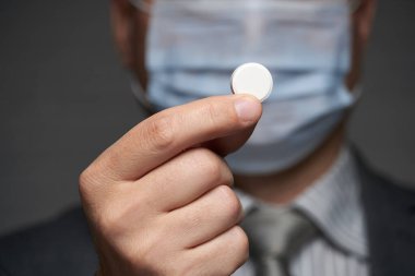 Yüzünde antivirüs şahsi koruması için maske takan bir adam ilaç gösteriyor - sağlık ve tıp konsepti, önleme ipuçları