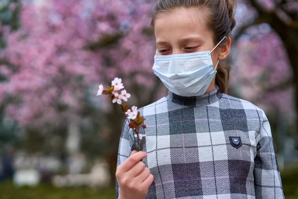 フェイスマスクを持つ女の子は街の屋外にあり 木を咲かせ 春の季節 開花時間 ほこりの多い空気からのアレルギーと健康保護の概念 — ストック写真