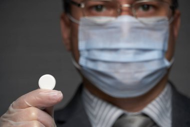 Yüzünde antivirüs şahsi koruması için maske takan bir adam ilaç gösteriyor - sağlık ve tıp konsepti, önleme ipuçları