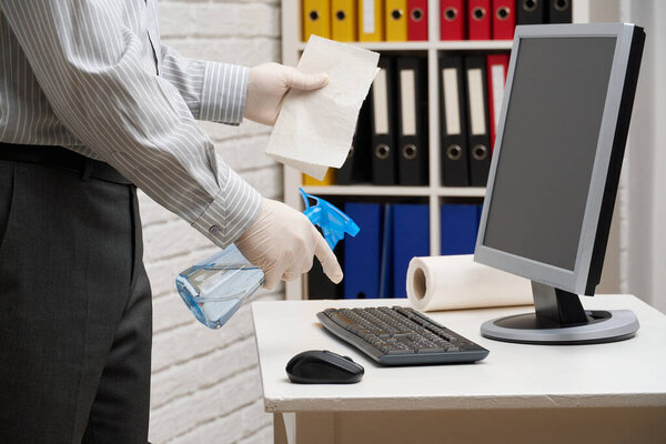 концепция очистки или дезинфекции офиса - бизнесмен чистит рабочее место, компьютер, стол, использует аэрозольный пистолет и бумажные салфетки. Очистка поверхности от микробов, вирусов и грязи
.