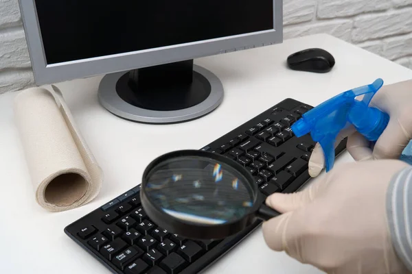 concept of cleaning or disinfecting the office - a businessman cleans the workplace, computer, desk, uses a spray gun and paper napkins. Cleaning surfaces from microbes, viruses and dirt.