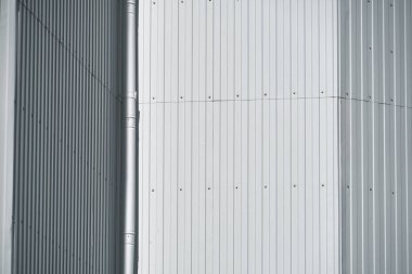 Duvara beyaz metal kaplama ve arka plan olarak boşaltma borusu