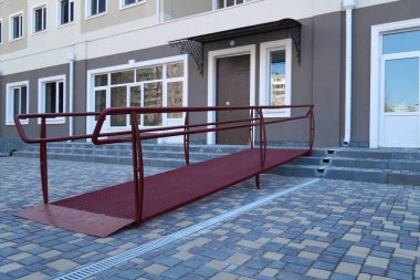 Çok katlı bir binanın girişi için tekerlekli sandalye giriş rampası, şehir sokağı ve kaldırım taşları
