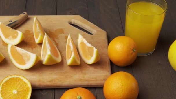 木製のテーブルの上に新鮮なオレンジ 全体とスライス 柑橘類のスライスでいっぱいのプレート — ストック動画