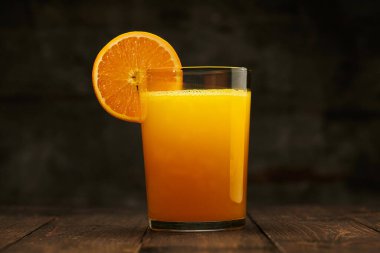 Tahta bir masada taze portakal suyu ve meyve suyu. Doğal ve sağlıklı yiyecek ve içecek. Bir bardak kokteyl ve bir dilim meyve.