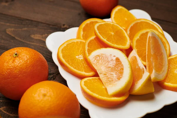 Frische Orangenfrüchte Ganz Und Scheiben Geschnitten Auf Einem Teller Dunkler — Stockfoto