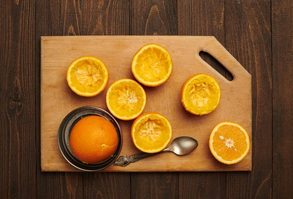 Fresh orange fruits whole and squeezed on a wooden table, cutting board - natural and healthy food. Glass of fruit cocktail.