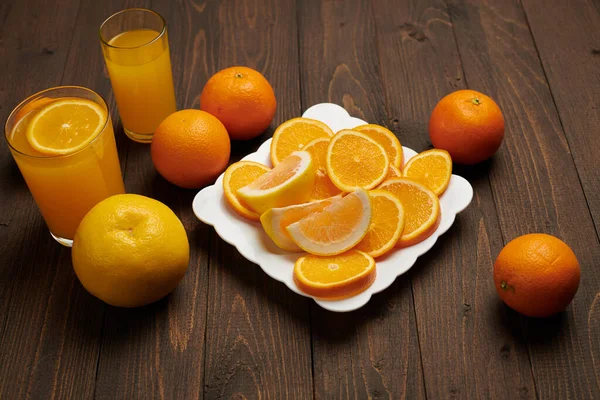 新鲜的橙色水果 切碎在黑暗的木制背景上 自然健康的食物 一杯水果鸡尾酒 — 图库照片
